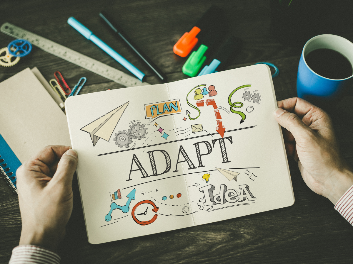 Notebook open with word 'adapt' written and diagrams shown