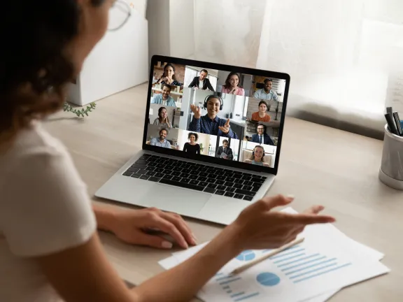Back view of female employee on video call with colleagues.