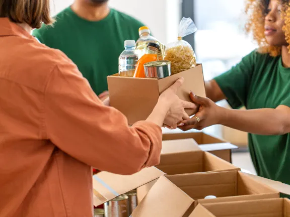 A woman handing another a box of food and supplies