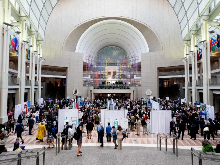 Wide angle shot of the Ronald Reagan Building Atrium with people mingling amongst Exhibit Hall booths